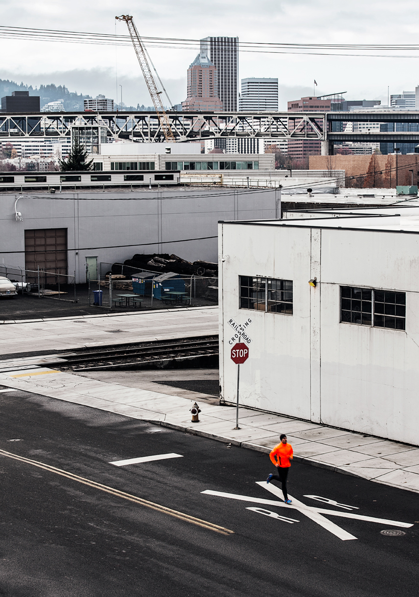 Runner in orange coat running on street in urban city landscape  — Studio 3, Inc.