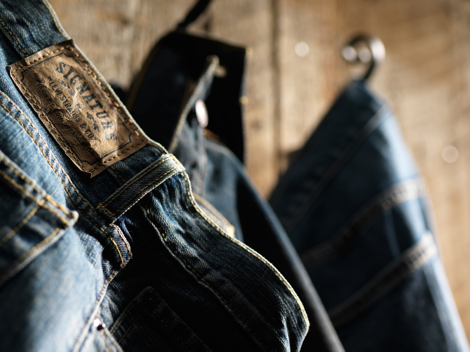 Close up of Levi Strauss & Co. Signature blue jeans clothing label with jean jacket hanging on hook in background  — Studio 3, Inc.