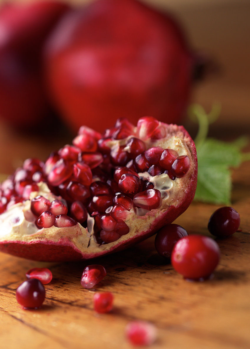 pomegranate seeds on wooden table   — Studio 3, Inc.