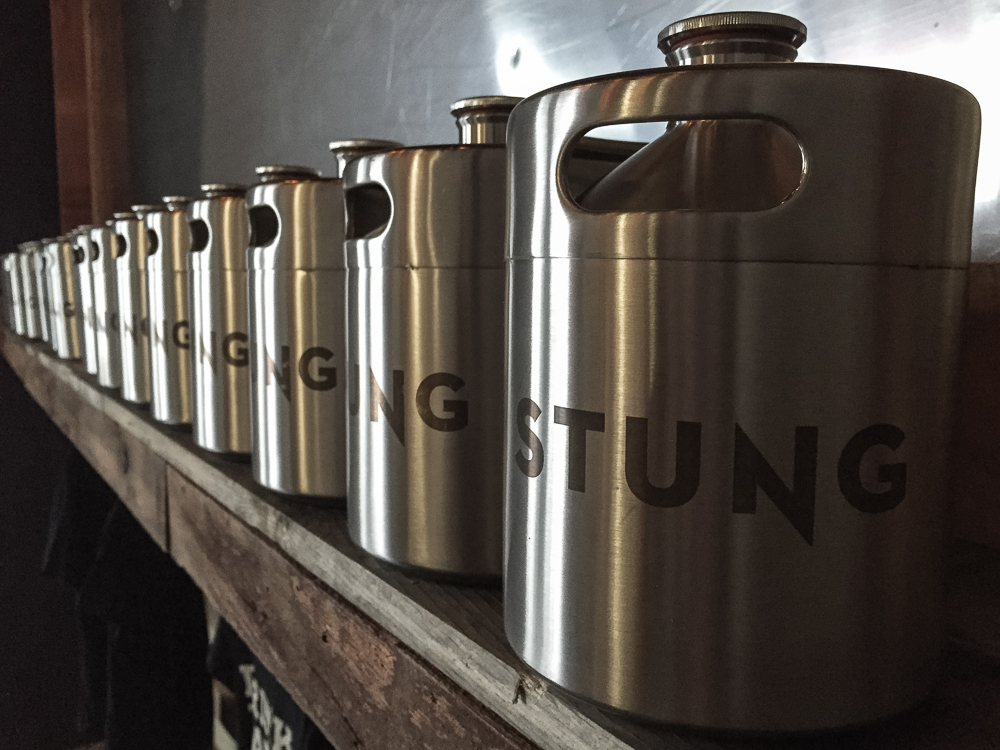 Row of stainless steel Stung Fermented mead jars on shelf in meadery  — Studio 3, Inc.