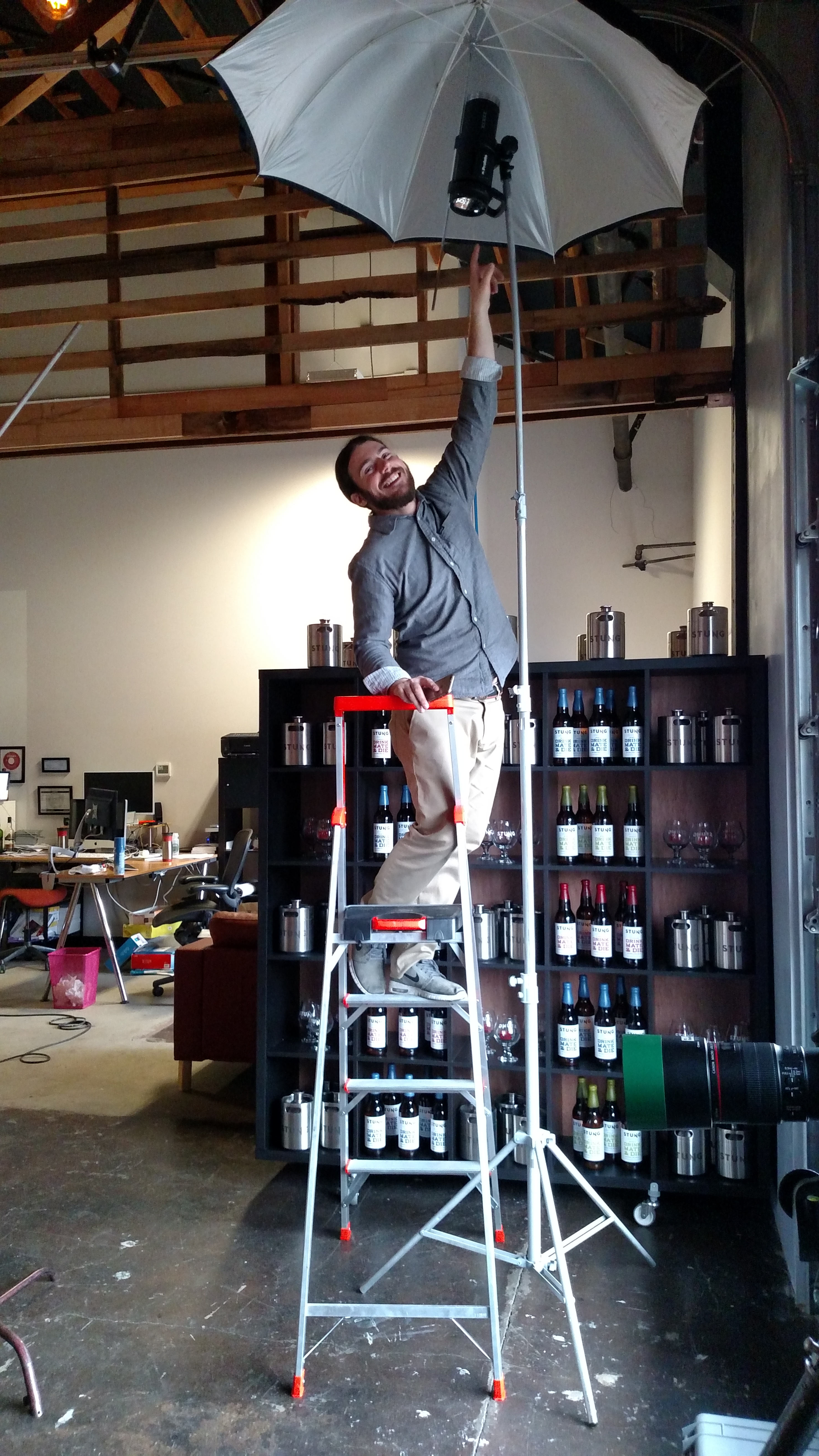 Assistant photographer Jonny Brandt adjusting lighting umbrella at the Stung Fermented photoshoot behind the scenes  — Studio 3, Inc.