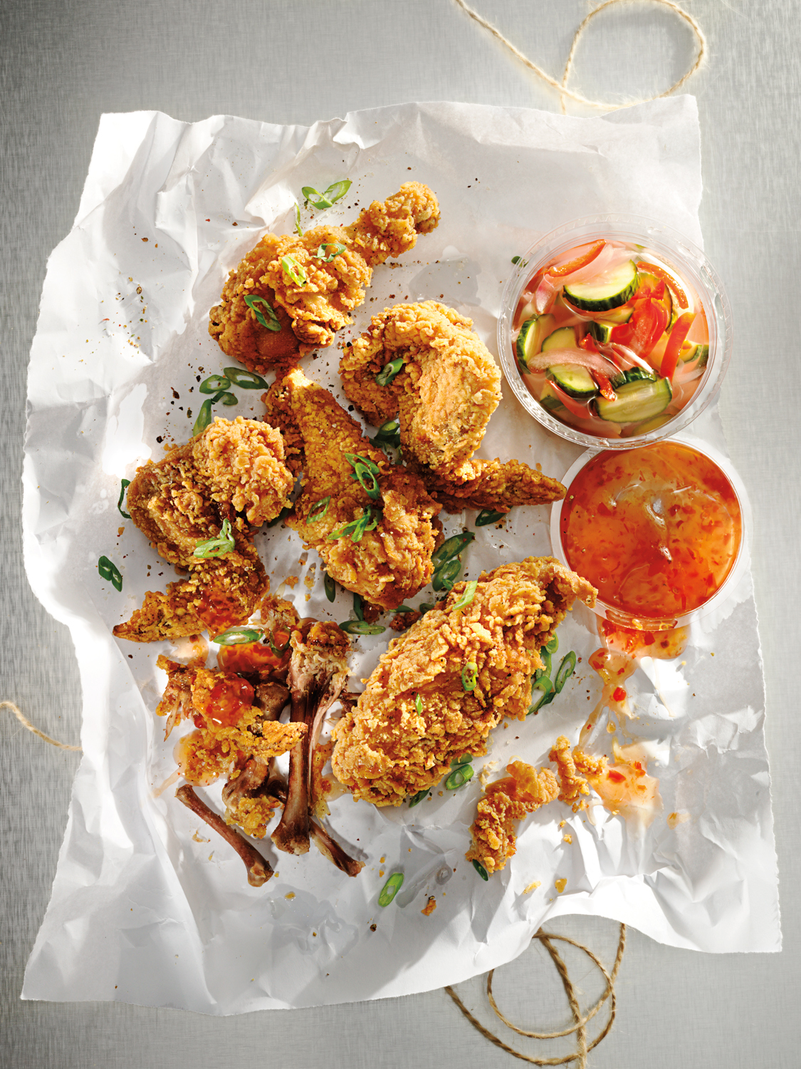 Spicy fried chicken pieces with Asian sauce on wax paper picnic lunch  — Studio 3, Inc.