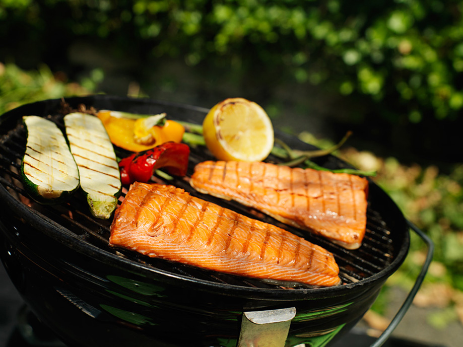 salmon on grill next to vegetables 